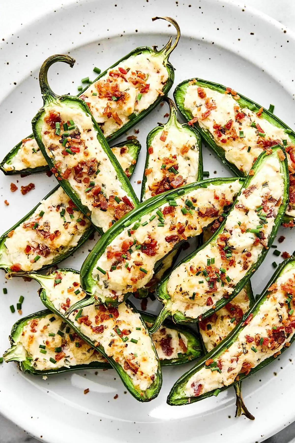 These jalapeño poppers are the ultimate party appetizer—especially for game day! They're cheesy, savory, and dotted with crispy bacon. A plate of jalapeñopoppers.