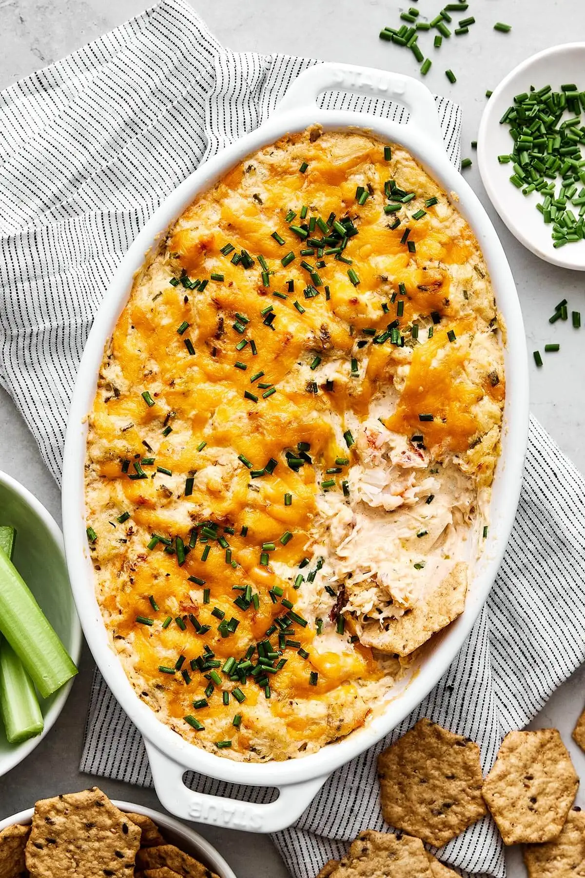 A baking dish with crab dip and crackers.