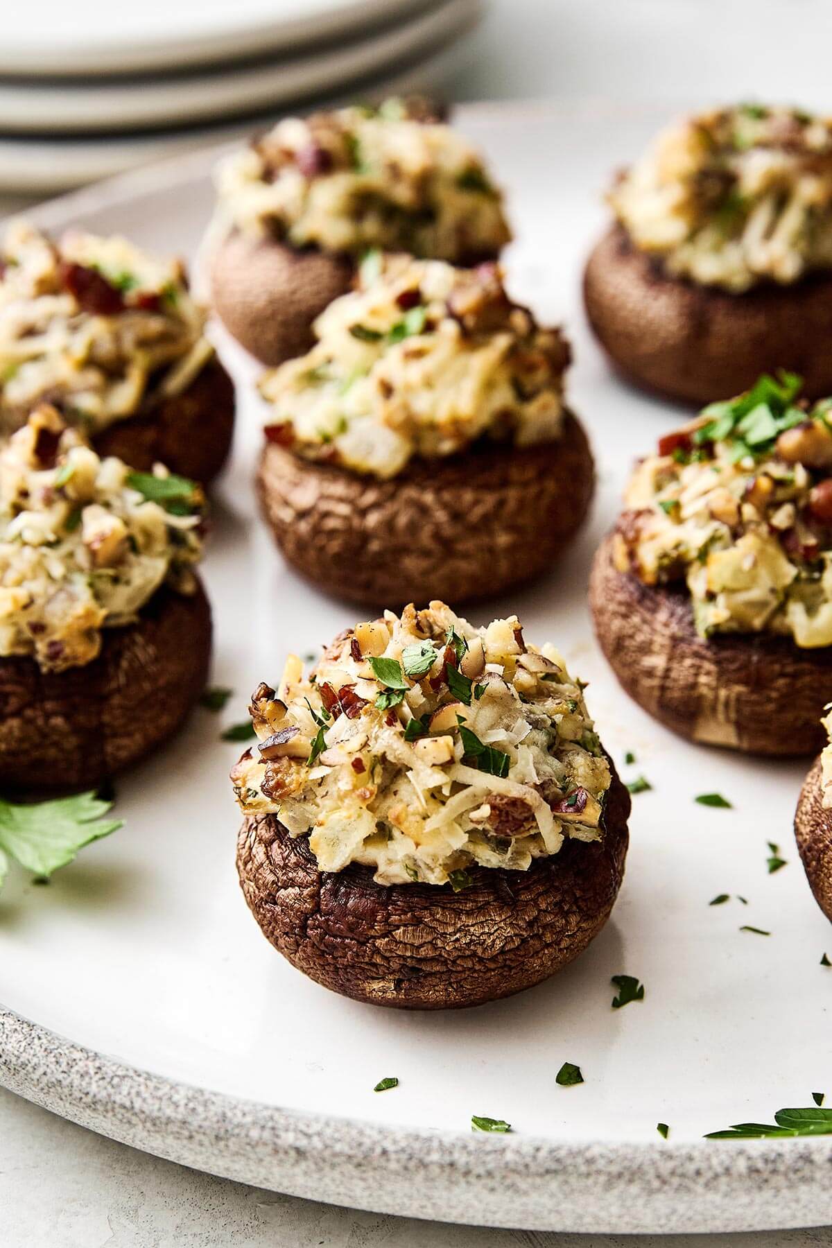 Stuffed mushrooms are always a holiday favorite! They're the perfect cheesy mushroom bite with hints of onion, herbs, and pecans. Stuffed mushrooms on a plate.