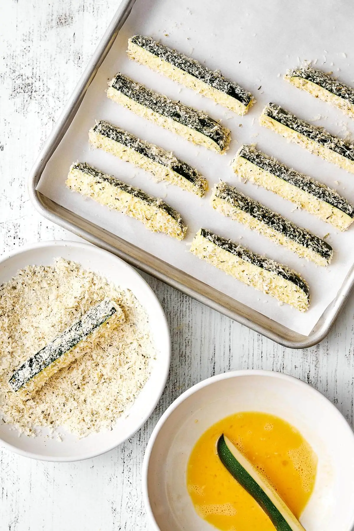 Coating zucchini fries with Parmesan cheese.