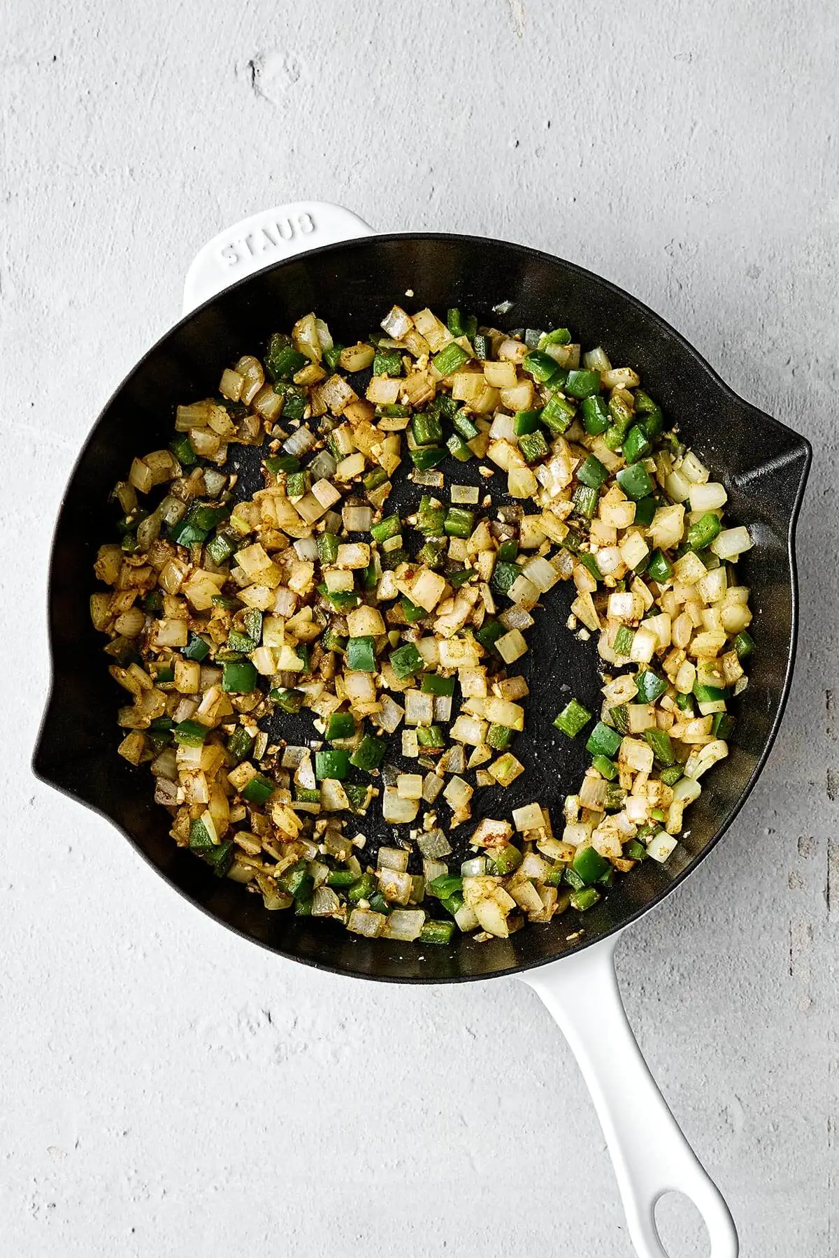 Sauteed onions and bell pepper in a pan.