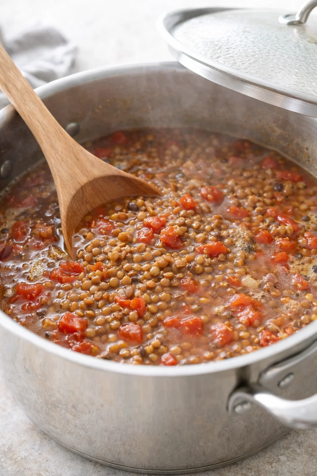 Spices and minced garlic sizzling in pot, lentils and diced tomatoes added, liquid beginning to boil.