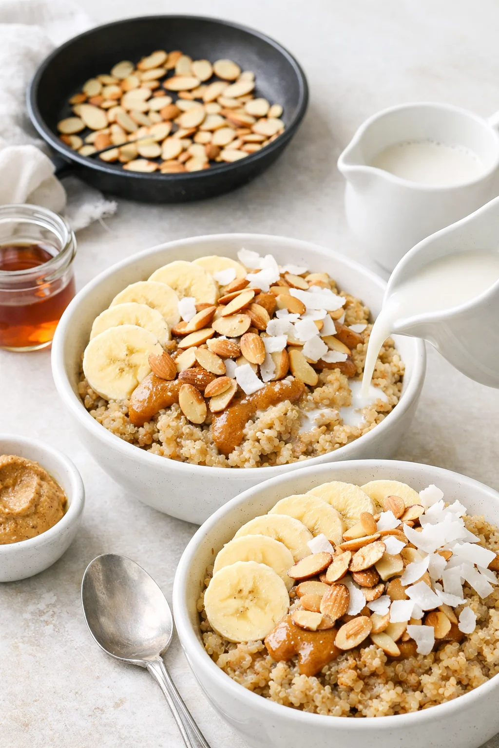 step-process-placeholder-9-12.png Sliced bananas, toasted almonds, and coconut flakes scattered atop warm quinoa bowls ready to serve.
