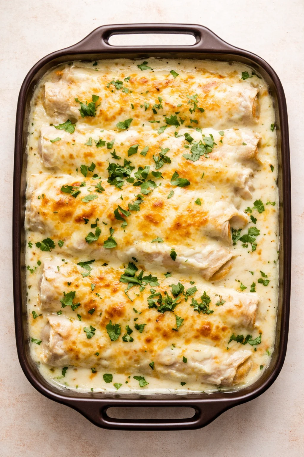 creamy baked chicken in a brown casserole, sprinkled with chopped parsley