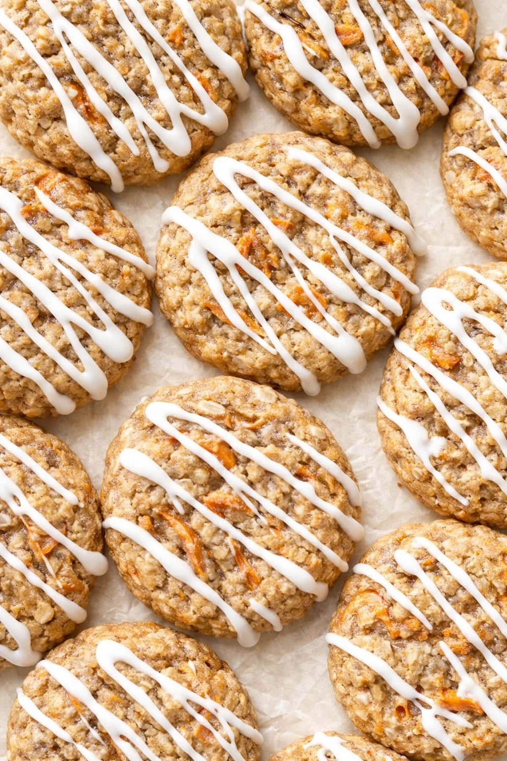 Close-up of round oatmeal cookies with white icing drizzle on parchment