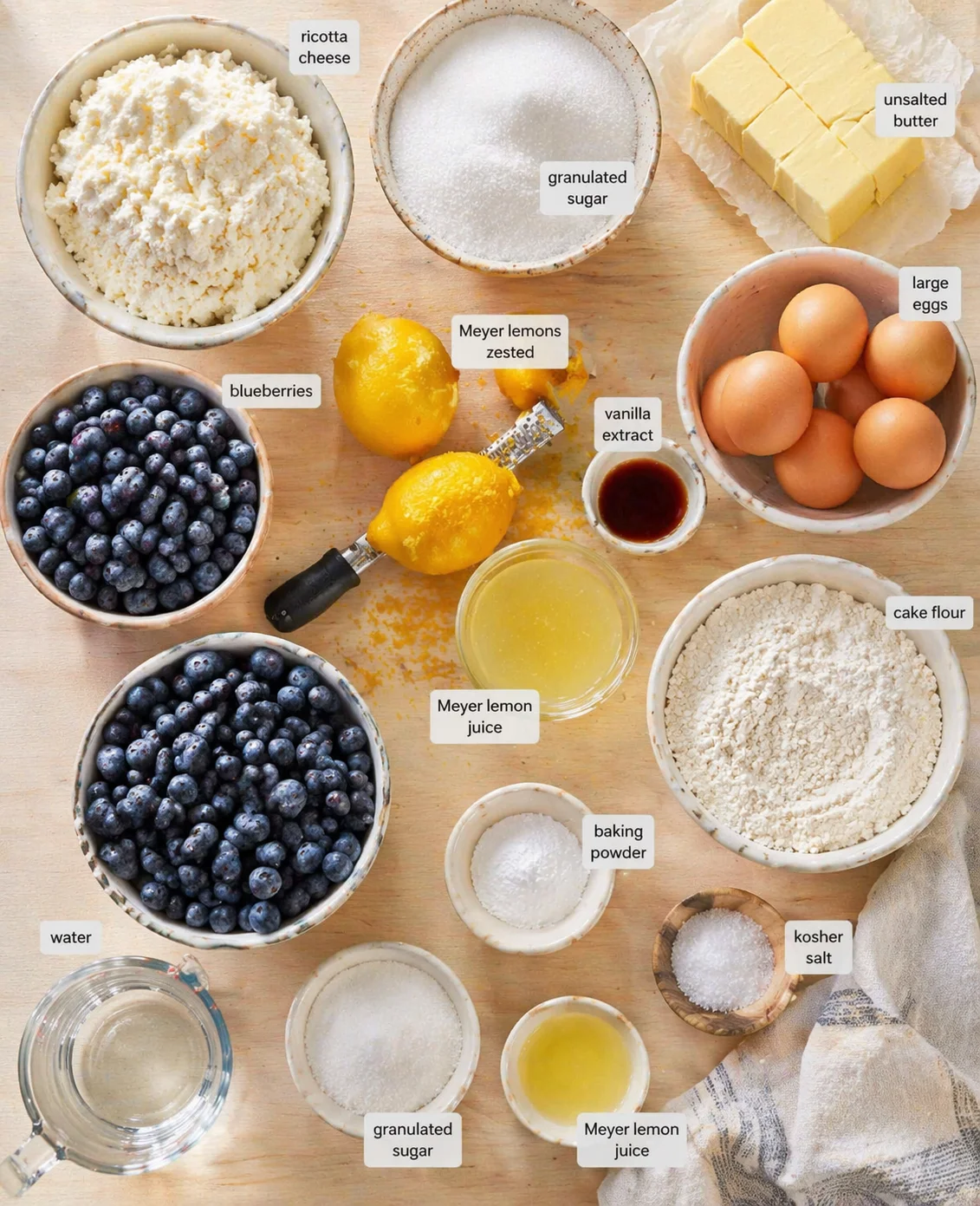 Overhead view of lemon-blueberry-ricotta cake ingredients arranged on a wooden surface.