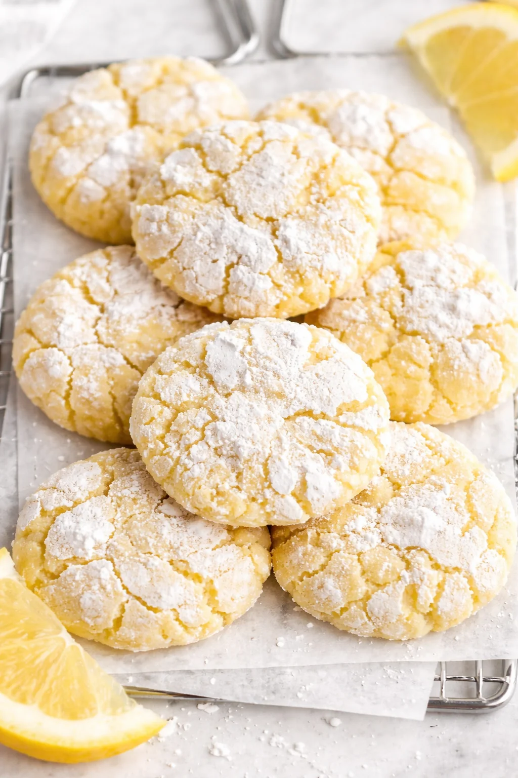Pile of lemon crinkle cookies dusted with powdered sugar on parchment