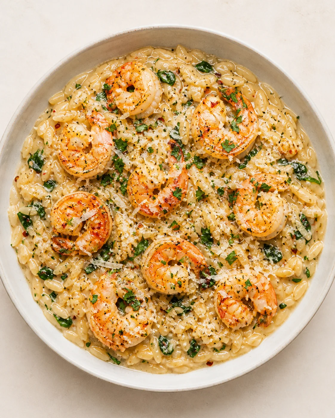 Creamy shrimp and orzo pasta in pale sauce, garnished with parsley.