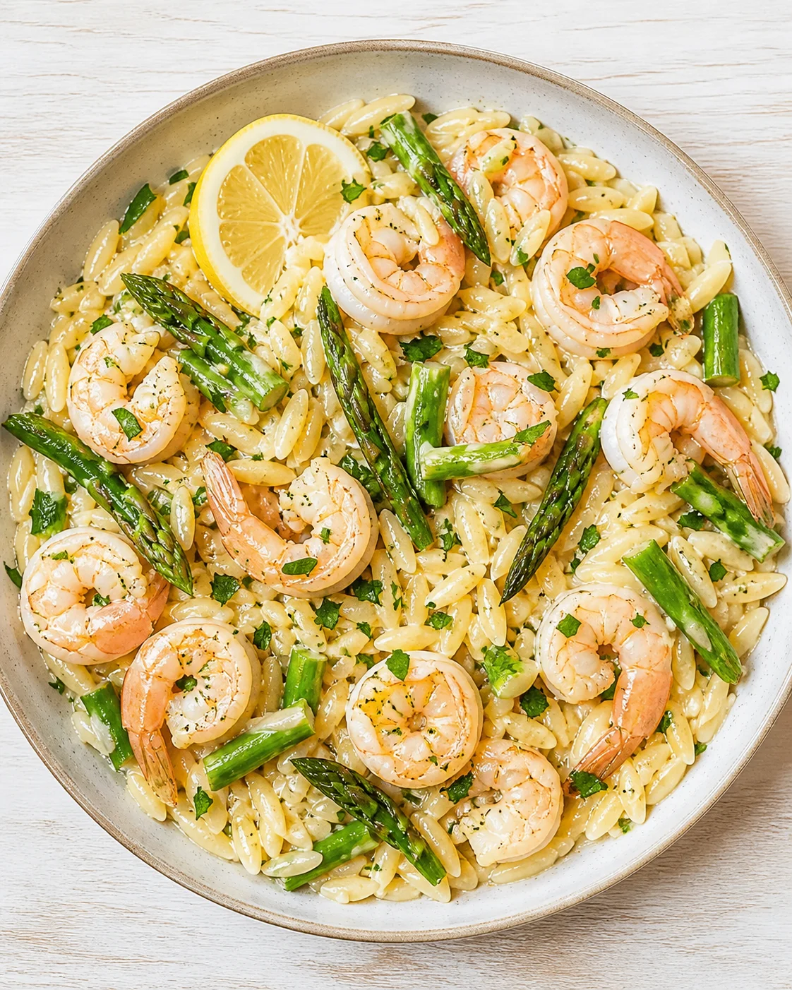 Creamy shrimp and asparagus over orzo pasta, with a lemon wedge