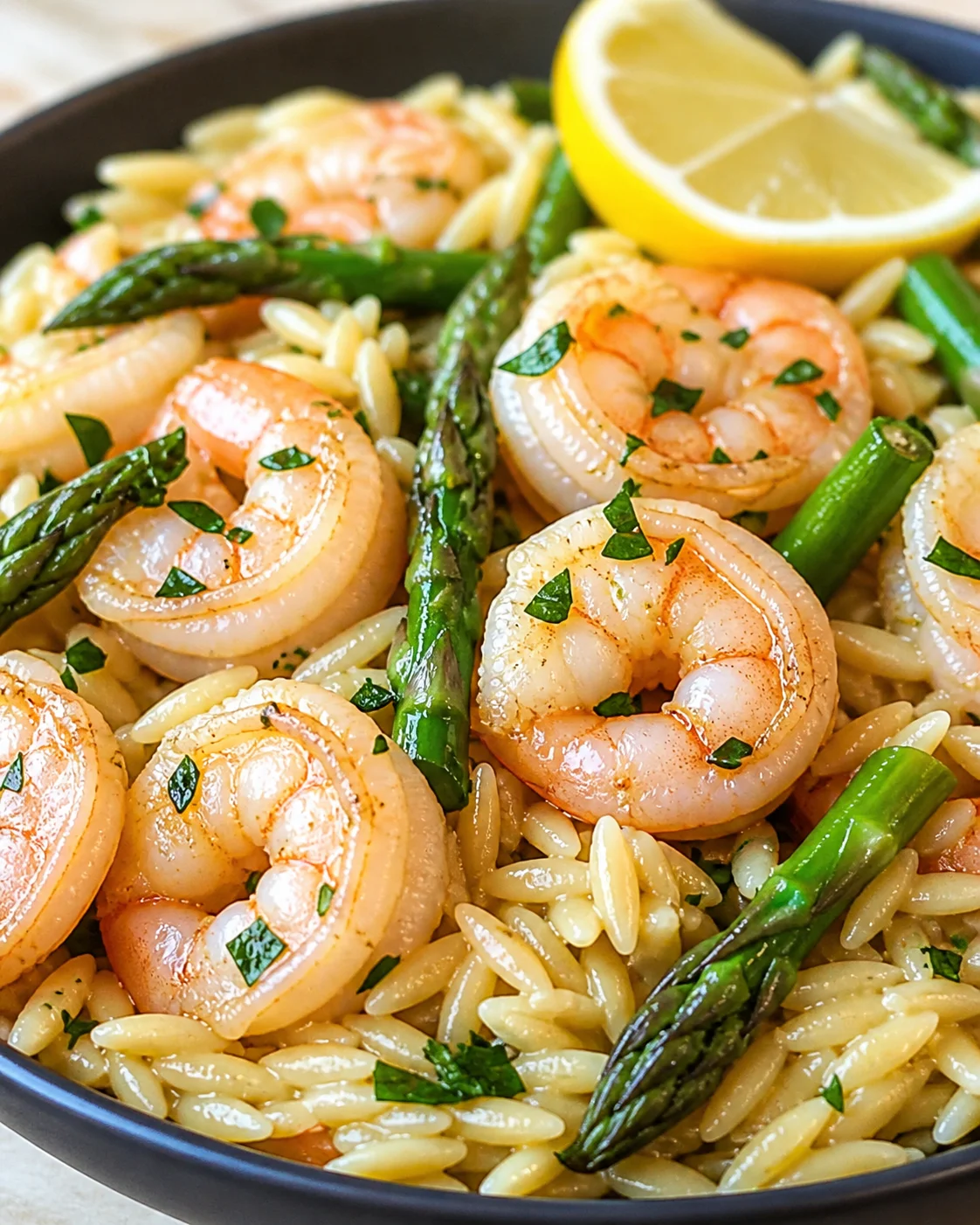plump shrimp over orzo pasta with asparagus, parsley, and a lemon wedge.