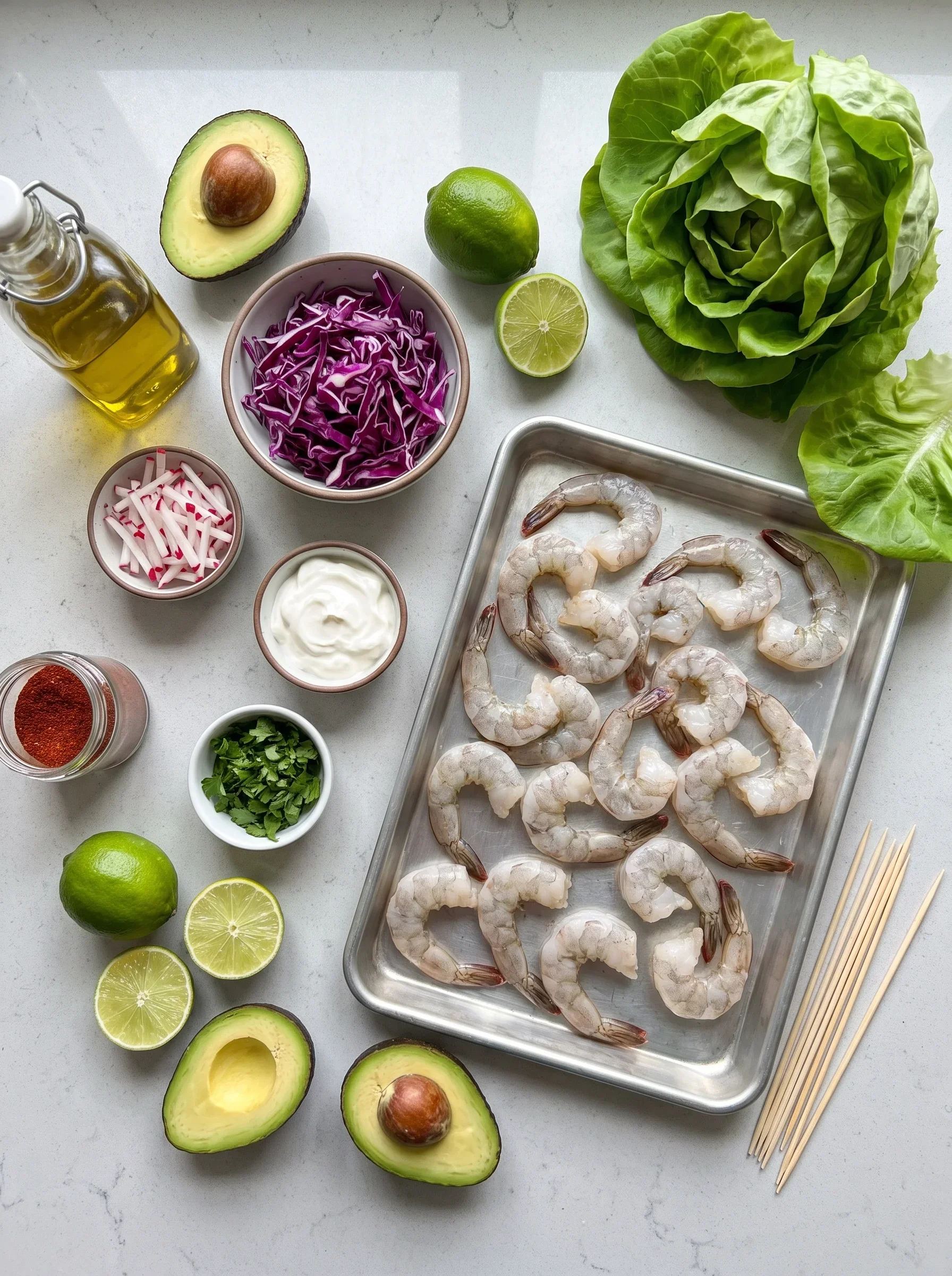 All ingredients for shrimp lettuce wraps on a white surface, including shrimp, avocado, and slaw.